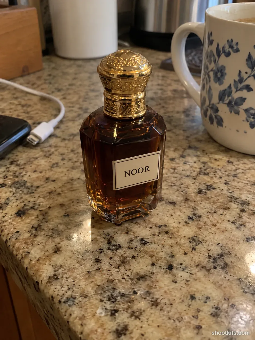 Before: a casual phone photo of an oud perfume bottle